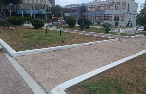 Ισόπεδος, πλατύς διάδρομος προς την είσοδο του Δημαρχείου, περιβάλλεται από πράσινο και περνάει μέσα από παρτέρια.